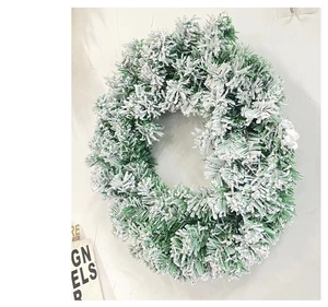 Detailed view of snowy artificial pine wreath with realistic white flocking on white wall