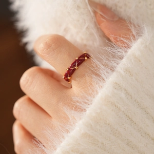 Detail of red enamel gold plated ring with quilted pattern on a white knit sleeve
