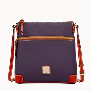 Detail of purple pebble leather crossbody bag with brown trim and golden zipper pocket