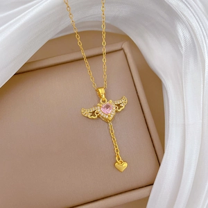 Detailaufnahme der goldenen Flügelkette mit rosa Herz-Edelstein auf weißem Stoff