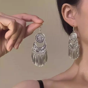 Detail of silver vintage flower earrings with ethnic crescents and metal tassels