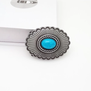Oval silver belt buckle with turquoise inlay and sunburst scallop edges on white base
