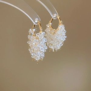 Macro shot of cluster crystal fringe earrings with gold-plated hoops on a display stand