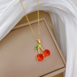 Collier luxueux en titane doré avec pendentif cerise en cristal rouge et feuille verte