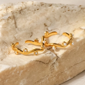 Close-up of 18K gold plated wave ear cuffs with white pearls and zircons on stone