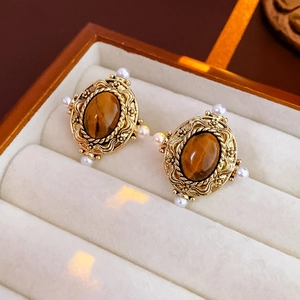 Détail de boucles d'oreilles vintage dorées avec pierre œil de tigre et perles