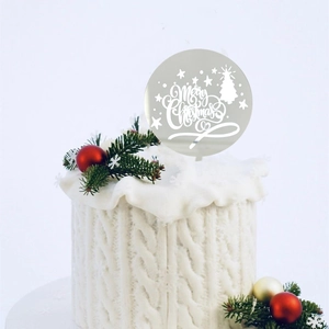 Detail of silver acrylic Merry Christmas cake topper with tree and star cutouts on cake