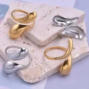 Detailed close-up of gold and silver irregular water drop rings on a stone surface