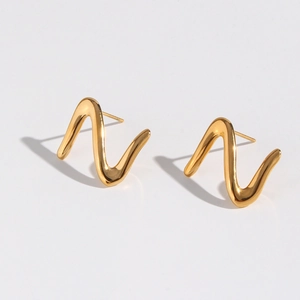 Macro detail of minimalist gold zigzag earrings featuring a fluid metallic wave design