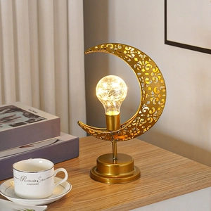 Détail de la lampe croissant de lune dorée avec ampoule LED chaude sur bureau bois
