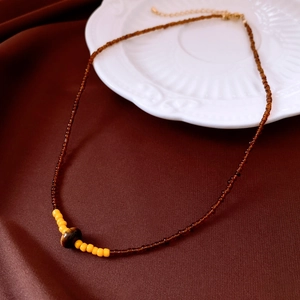 Gros plan d'une perle œil de tigre et d'un collier de perles marron sur de la soie