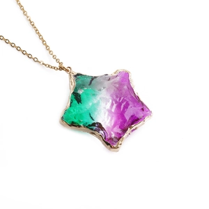Macro shot of gold star pendant with multi-color gradient ice crackle texture on chain