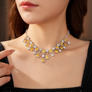 Close-up of model wearing luxury drop pendant necklace with yellow zircon and crystals