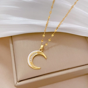 Detailed close-up of golden crescent moon pendant with white enamel and sparkling zircons
