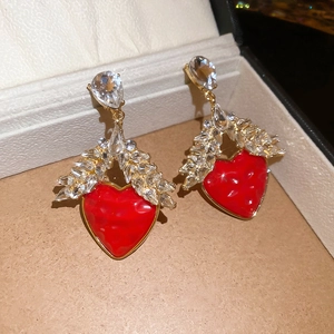 Détail macro de boucles d'oreilles en cœur avec des ailes en cristal dans un écrin