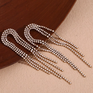 Macro detail of 18K gold plated arch earrings with sparkling cubic zirconia tassels