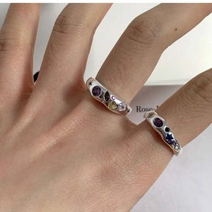 Detail of silver rings with colorful zircon stones and star engravings in a Y2K style
