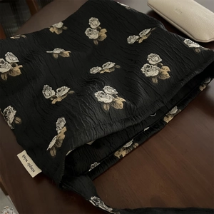 Detail of black textured fabric shoulder bag with elegant rose floral jacquard pattern