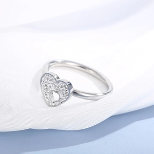 Close-up of silver hollow heart ring with sparkling pavé zircon on white fabric