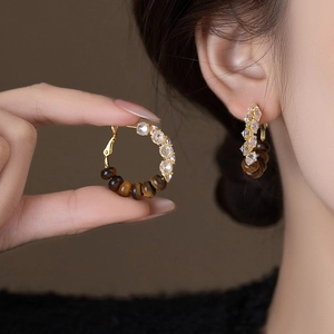 Elegant gold hoop earrings with tiger eye stone and zircons shown on model
