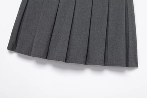 Detailed macro view of dark grey pleated fabric and hem stitching on women skirt