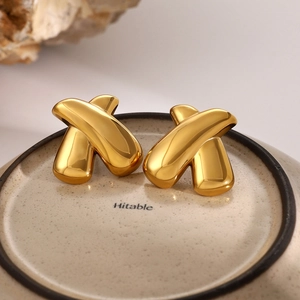 Macro view of 18k gold plated chunky X-shaped earrings with polished finish on stone