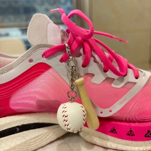 Detailed macro view of a mini baseball and wooden bat keychain on a pink sneaker