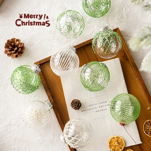 Transparent Christmas ornaments with green stars and sequins on white fur background