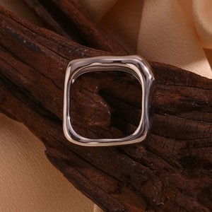 Vue macro d'une bague carrée argentée sur bois et tissu beige de qualité