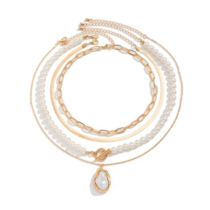 Detail of layered gold necklaces with snake chain and baroque pearl pendant with T-bar clasp