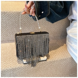 Macro shot of luxury black clutch bag with sparkling rhinestone fringe and silver bead handle