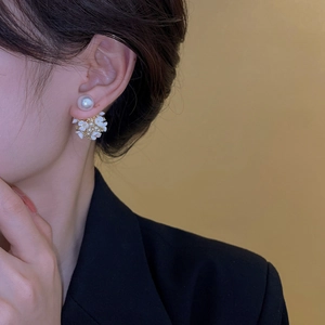 Gros plan d'un mannequin portant des boucles d'oreilles perles et fleurs blanches