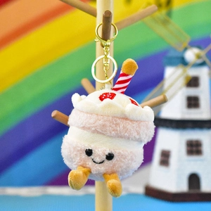 Detailed shot of a cute pink cake plush keychain with a smile and golden metal clasp.