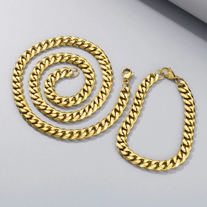 Detail view of gold Cuban link chain set including a necklace and bracelet on gray surface