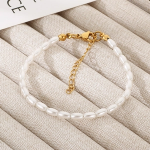 Detailed view of elegant oval pearl bracelet with gold lobster clasp on beige jewelry tray