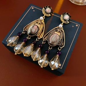 Detailed shot of vintage gold flower earrings with purple tassels on a navy star box