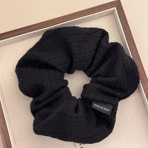 Detail of black knitted scrunchie with woven texture and Made in Korea label