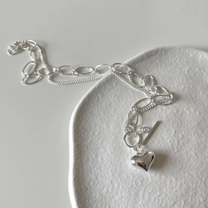 Detail of a silver double-layer heart necklace featuring mixed chains and OT toggle clasp
