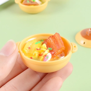 Macro shot of a miniature resin clay noodle bowl held by fingers showing small size