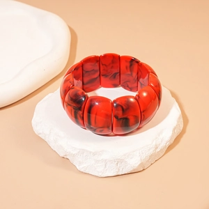 Detail of red and black marbled acrylic geometric stretch bracelet on stone base