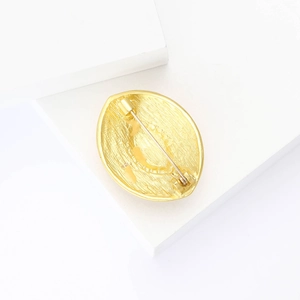 Detail view of the golden metal teardrop brooch back with pin clasp on white base