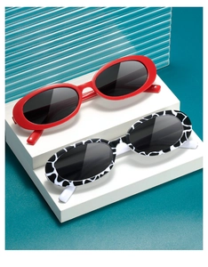 Detail of red and cow print oval sunglasses arranged on white blocks over blue background