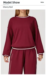 Detail of cherry red sports sweatshirt with white contrast stripes and wide-leg pants