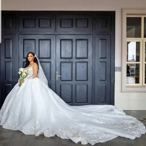 Elegante abito da sposa bianco in pizzo con maniche lunghe e uno strascico lungo