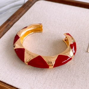 Close-up of vintage gold open bangle with red triangle enamel inlay and brushed texture