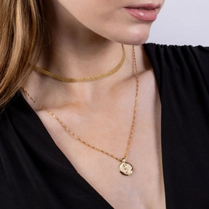 Detail of layered gold necklaces featuring a rose relief pendant and mesh chain