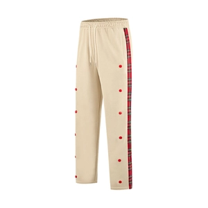 Detail of beige joggers featuring plaid side stripes and decorative red button fasteners