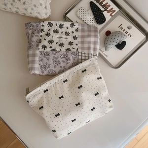 Detail of floral and polka dot fabric pouches with hair accessories in a metal tray