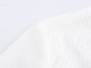 Macro shot of white textured crepe fabric showing detailed irregular pleats on the shirt