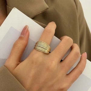 Chunky layered gold rings with textured finish worn by a model in a high-fashion style